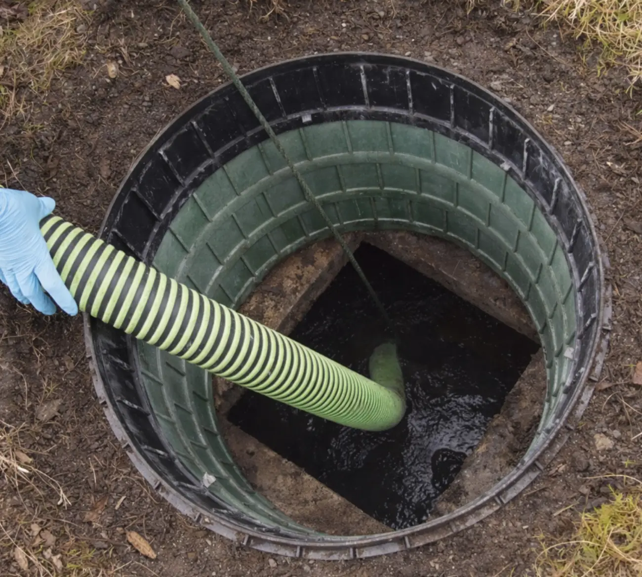 A True Septic pump hose lowered into an open septic tank